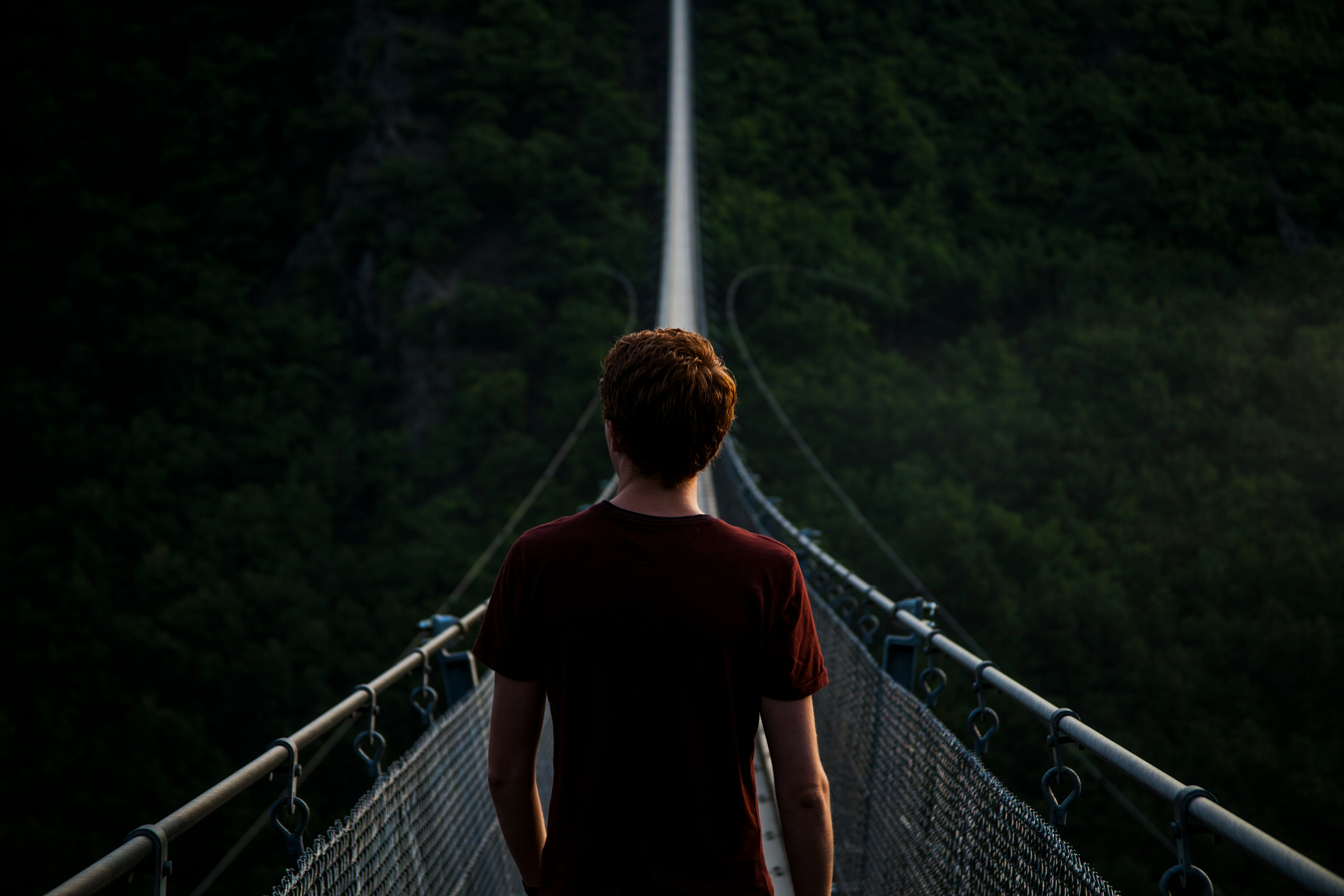 man standing alone on hanging bridge